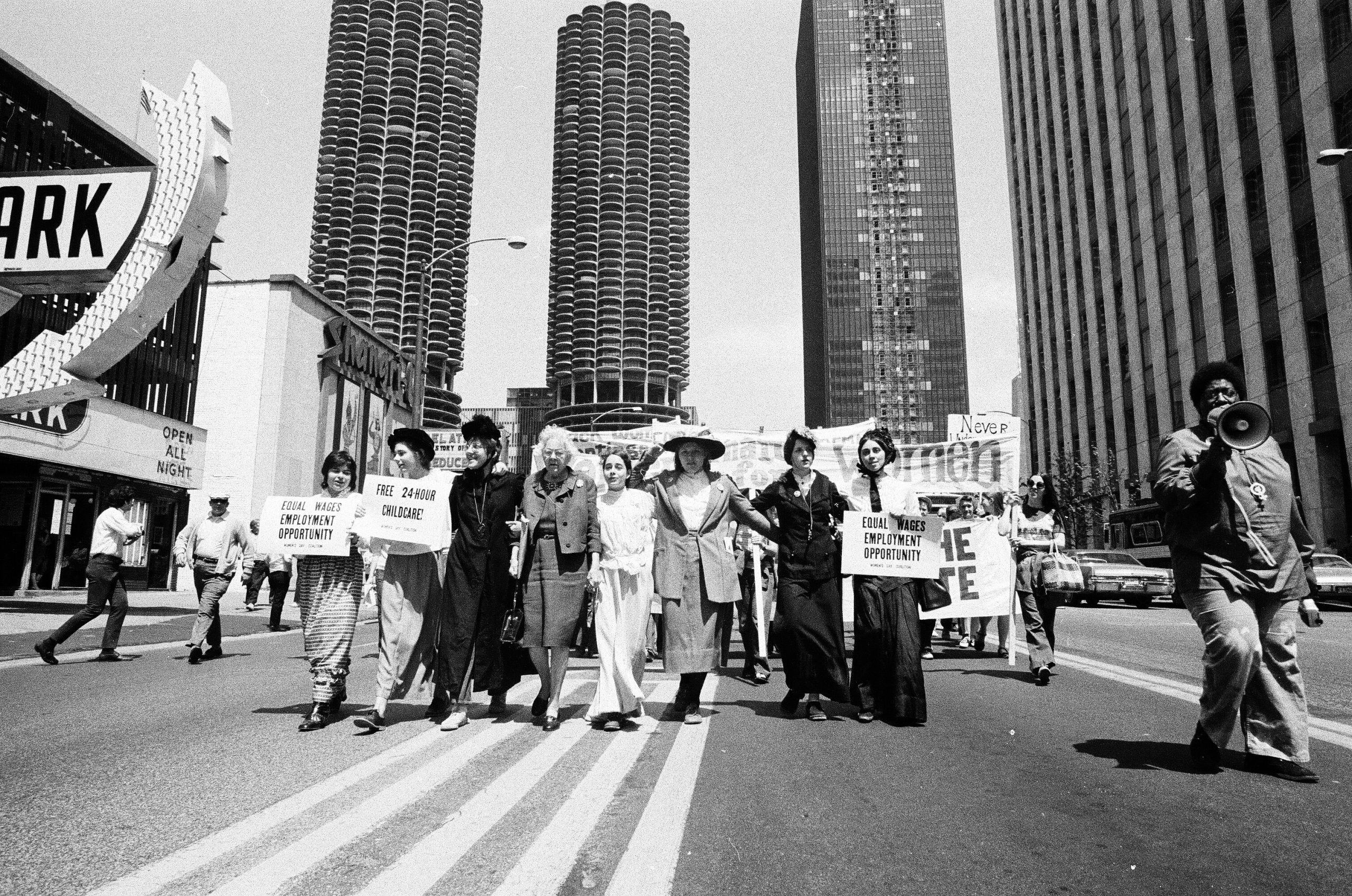 Black and white photograph of women marching down State Street with women's liberation banners, 1971
